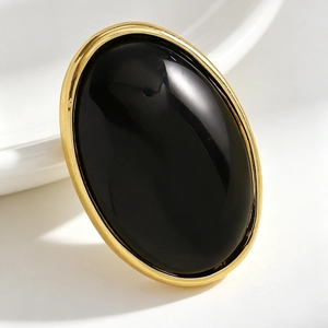 Close-up of a vintage oval earring with a black resin center and gold-tone frame.