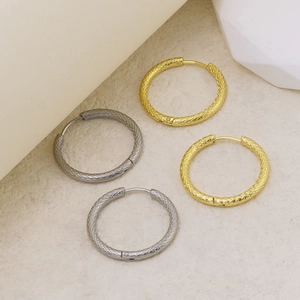 Detailansicht goldener und silberner Creolen mit feiner Gitterstruktur und Metallglanz