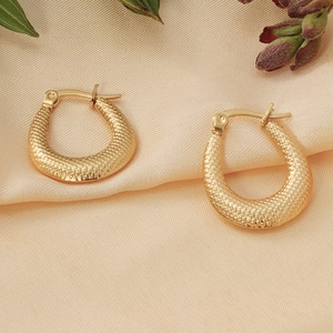 Detail of 18K gold plated hoop earrings with textured snakeskin pattern on silk