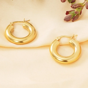 Detailed close-up of 18K gold-plated stainless steel hoop earrings on soft satin silk