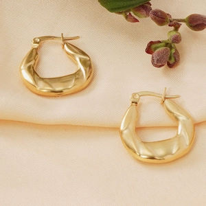 Golden 18K gold plated stainless steel snake pattern earrings on beige silk background