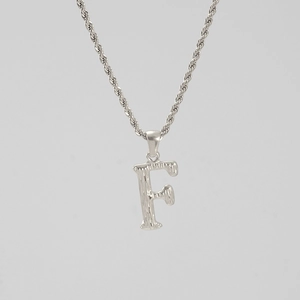 Macro detail of silver letter F pendant with hammered texture and stainless steel rope chain
