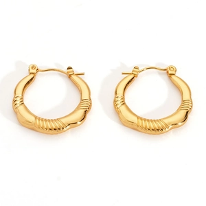 Dettaglio macro di orecchini a cerchio in oro 18K con trama ondulata e chiusura sicura