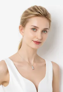 Silver cylindrical perfume bottle pendant necklace shown on a model with white background