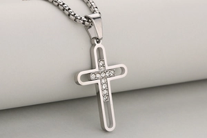 Détail macro du pendentif croix en acier inoxydable avec diamants et design ajouré