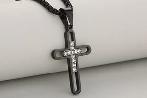 Gros plan du pendentif croix noire avec incrustation de cristaux et chaîne à mailles carrées