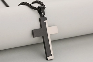 Close-up of two-tone stainless steel cross pendant with black diagonal texture and silver mirror