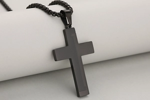 Macro detail of black stainless steel cross pendant with diagonal engraved textures