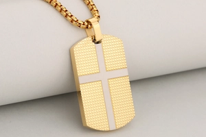 Close-up of gold plated stainless steel dog tag pendant with textured cross inlay