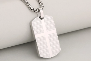 Macro view of stainless steel dog tag necklace with cross pattern and grid texture