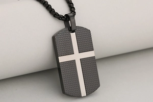 Detail of cross dog tag pendant with black grid texture and silver cross inlay