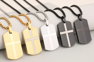 Close-up of rectangular cross dog tag pendants in gold, silver, and black finishes