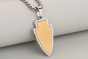 Détail macro du pendentif flèche avec texture or 18K brossé et chaîne argentée