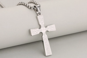 Macro detail of silver stainless steel cross pendant with engraved Lord's Prayer text