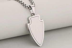 Détail macro du pendentif flèche en acier inoxydable argenté avec fini brossé et poli