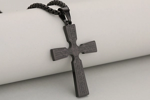 Close-up of black stainless steel cross pendant featuring engraved Lord's Prayer text
