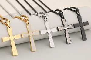 Macro detail of stainless steel cross necklaces with engraved Our Father prayer in three colors