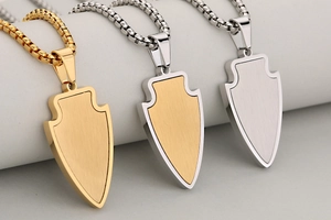 Détails des pendentifs boucliers en finitions or, argent et bicolore avec texture