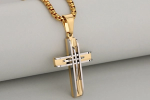 Macro shot of layered gold and silver stainless steel cross pendant with box chain