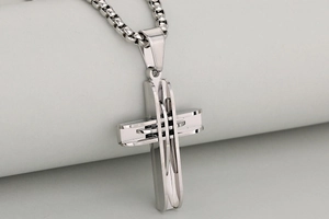 Detailed macro view of silver cross pendant with layered hollow design and box chain