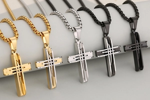 Detail of layered stainless steel cross pendants in gold, silver, and black finishes