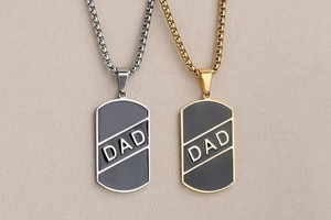 Primer plano de colgantes dog tag en oro y plata con esmalte negro y grabado DAD de moda