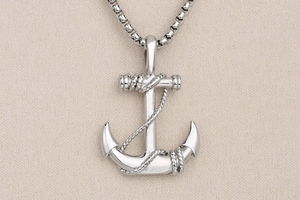 Dettaglio macro del ciondolo ad ancora nautica con trama a corda su collana d'acciaio