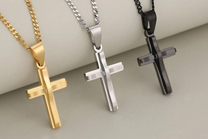 Detail of layered stainless steel cross pendants in gold, silver, and black finishes