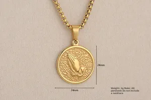 Macro shot of 24mm gold praying hands pendant with detailed embossed metal surface