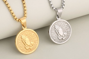 Detailed close-up of gold and silver praying hands relief on vintage coin necklaces