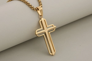 Macro detail of a hollow double-layer gold cross pendant with a polished box chain