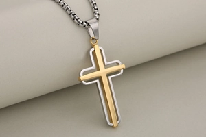 Macro shot of two-layer hollow cross pendant in gold and silver stainless steel