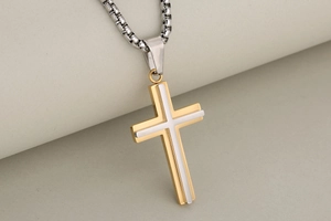 Detailed close-up of double-layer stainless steel cross pendant in gold and silver