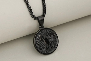 Macro detail of gunmetal praying hands pendant with hammered texture on black bead chain