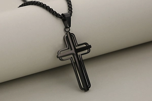 Detail view of black stainless steel cross pendant featuring a layered hollow geometric design