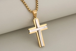 Close-up of dual-tone gold and silver cross pendant with a polished box chain necklace