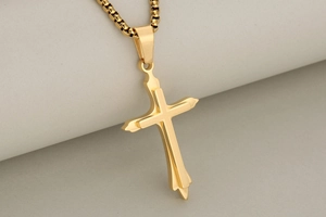 Macro detail of a 3D double-layered gold stainless steel cross pendant with box chain