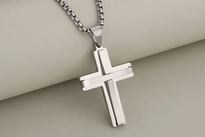Close-up of silver stainless steel cross pendant with brushed metal and polished finish