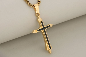 Macro shot of double-layer gold stainless steel cross pendant with black enamel inlay