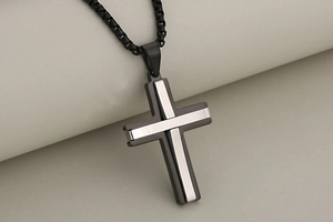 Detail of two-tone black and silver stainless steel cross pendant with box chain link