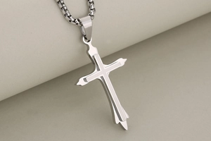 Macro shot of silver stainless steel cross pendant with brushed and polished dual layers