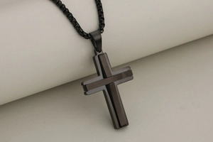Detailed macro view of a matte black cross pendant with a double-layered steel design