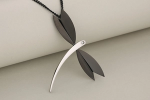Macro shot of dragonfly pendant showing silver polished body and matte black wings