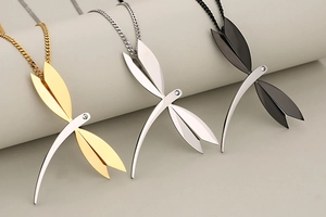 Detail view of dragonfly pendants in gold, silver and black finishes on jewelry display