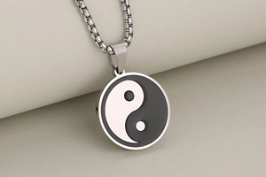 Macro detail of silver stainless steel Tai Chi Yin Yang pendant on a box chain