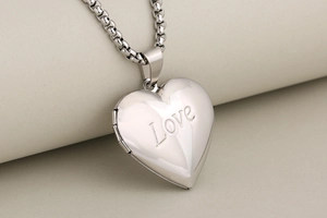 Macro shot of silver heart locket necklace with Love engraving and box chain detail