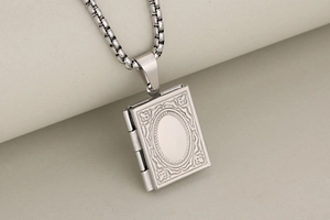 Macro view of book-shaped locket pendant with vintage floral engraving and hinge detail