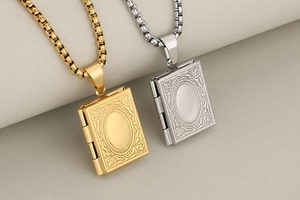 Close-up of vintage engraved book locket pendants in gold and silver stainless steel