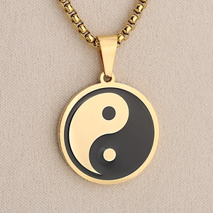 Polished gold stainless steel necklace with Yin Yang Tai Chi round pendant on beige fabric