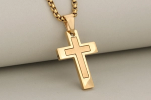 Macro detail of gold cross pendant with dual-layer brushed and polished stainless steel finish